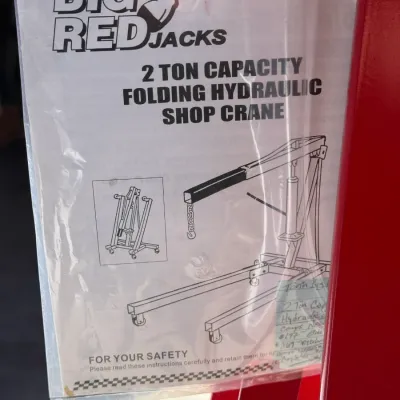 Sale Photo Thumbnail #510: Instruction manual for a Torin Big Red Jacks 2-ton capacity folding hydraulic shop crane, attached to a piece of red equipment.