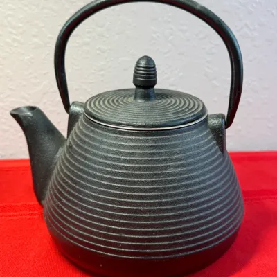 Sale Photo Thumbnail #464: Japanese-style black cast iron teapot featuring a ridged body and matching lid with a decorative finial.