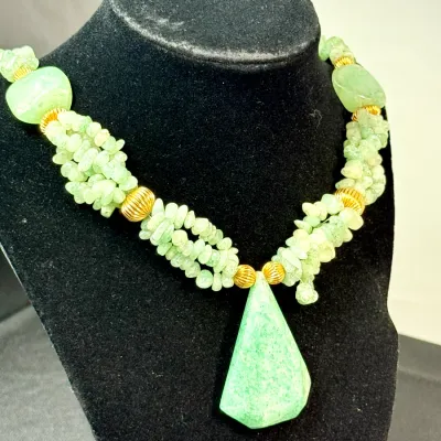 Sale Photo Thumbnail #348: Multi-strand green aventurine chip necklace featuring smooth, light green stone accent beads and a large teardrop pendant with ribbed gold-tone spacer beads.