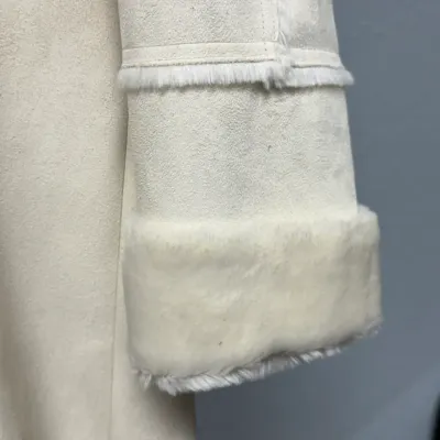 Sale Photo Thumbnail #853: Close-up of a white faux suede or shearling coat sleeve showing plush fur-lined cuffs and trim detail.