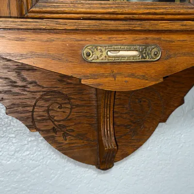 Sale Photo Thumbnail #369: Detail of an antique carved oak wall clock base featuring a built-in spirit level and ornate scroll carvings.