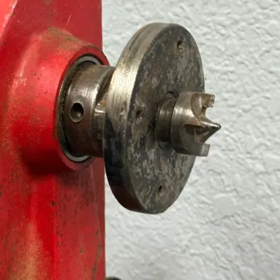 Sale Photo Thumbnail #553: Close-up of a red wood lathe headstock fitted with a faceplate and spur center attachment.