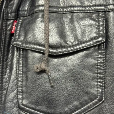 Sale Photo Thumbnail #879: Black Levi's faux leather jacket featuring a button-flap chest pocket with signature red logo tab and a hooded drawstring detail.