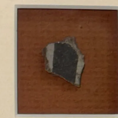 Sale Photo Thumbnail #482: Framed Native American pottery shard artifact featuring a dark painted band on a light ground.