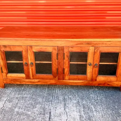 Sale Photo Thumbnail #310: Rustic wood media console featuring four glass-front doors with metal ring pulls and interior shelving.