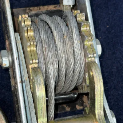 Sale Photo Thumbnail #657: Heavy-duty ratchet cable puller winch with wound steel wire rope, showing light surface wear.