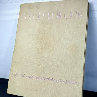 Sale Photo Thumbnail #429: Vintage hardbound copy of Audubon's Birds of America, featuring fifty selections with commentaries by Roger Tory Peterson, published by The Macmillan Company. The cream cloth cover shows visible spotting and shelf wear.