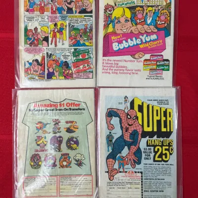 Sale Photo Thumbnail #759: Four vintage comic books from the 1970s, individually sleeved, showing back-cover advertisements for Hostess Fruit Pies, Bubble Yum, iron-on transfers, and Super Hang Ups posters.