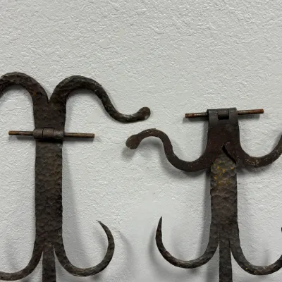Sale Photo Thumbnail #641: Pair of antique hand-forged wrought iron strap hinges with hammered finish and scroll detail, showing visible rust and patina.
