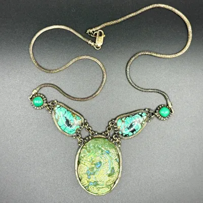Sale Photo Thumbnail #21: Vintage Asian-inspired statement necklace featuring turquoise matrix cabochons and a central carved green jade-style dragon pendant on a woven metal chain.