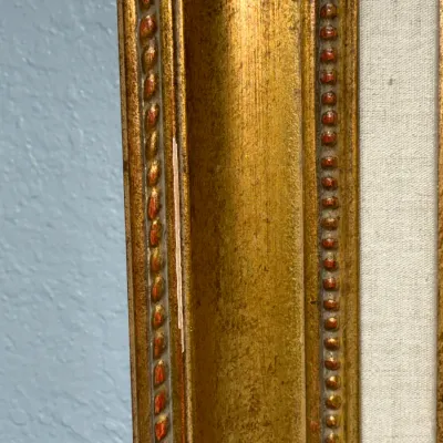Sale Photo Thumbnail #142: Close-up of an ornate gilt wood picture frame with beaded trim, showing a minor scratch along the left edge.