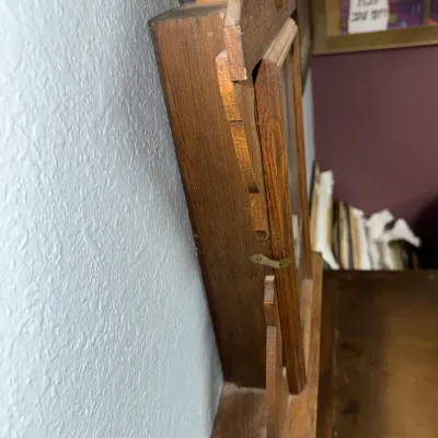 Sale Photo Thumbnail #374: Side profile of a vintage wooden wall clock showing the cabinet structure, glass front door with a brass latch, and mounting hardware.