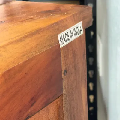 Sale Photo Thumbnail #255: Close-up of a warm-toned wooden furniture piece bearing an original 'Made in India' label on the upper edge.