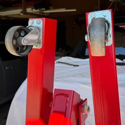 Sale Photo Thumbnail #507: Red steel engine hoist base legs equipped with heavy-duty caster wheels.