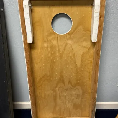 Sale Photo Thumbnail #926: Underside of a homemade wooden cornhole board featuring folding white-painted legs and wing nut hardware.