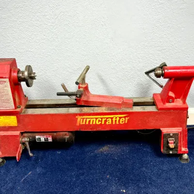 Sale Photo Thumbnail #551: PSI Woodworking Turncrafter Pro mini wood lathe in red finish, featuring an induction motor and adjustable tool rest.