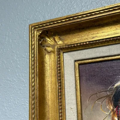 Sale Photo Thumbnail #155: Detail view of an ornate gilded wood picture frame featuring a beaded trim and fabric liner.