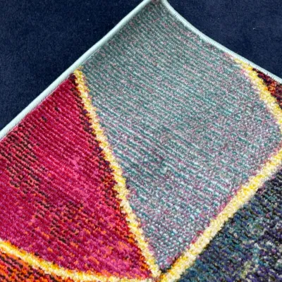 Sale Photo Thumbnail #728: Corner detail of a contemporary geometric area rug featuring bold blocks of pink, teal, yellow, and dark tones.