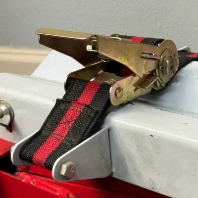 Sale Photo Thumbnail #528: Heavy-duty ratchet tie-down strap with gold-zinc plated hardware and black and red nylon webbing.