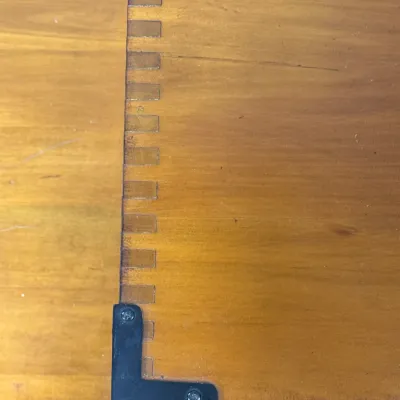 Sale Photo Thumbnail #211: Close-up detail of a wooden furniture piece, featuring box-joint joinery and a black metal L-bracket hardware accent.