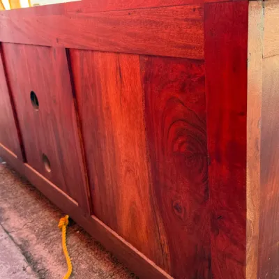 Sale Photo Thumbnail #316: Back panel view of a solid hardwood media console or credenza, featuring rich reddish-brown wood grain and cable pass-through holes.