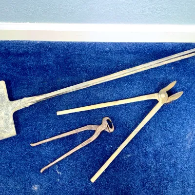 Sale Photo Thumbnail #574: Collection of vintage forged iron blacksmith tools, including a long shovel, metal tongs, and pliers.