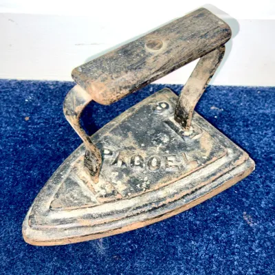 Sale Photo Thumbnail #595: Antique cast iron sadiron with a wooden handle grip, marked PACOEL 6, showing age-appropriate rust and wear.