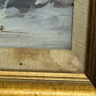 Sale Photo Thumbnail #450: Close-up detail of a framed oil painting depicting a stormy seascape, featuring a linen liner with minor staining inside a gilt and dark wood frame.
