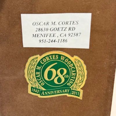 Sale Photo Thumbnail #495: Maker's mark and contact label for Oscar M. Cortes Woodcarving on the back of an artwork piece.