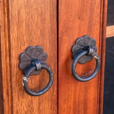 Sale Photo Thumbnail #313: Close-up of a wooden cabinet with ornate Asian-style dark metal ring handles mounted on flower-shaped backplates.