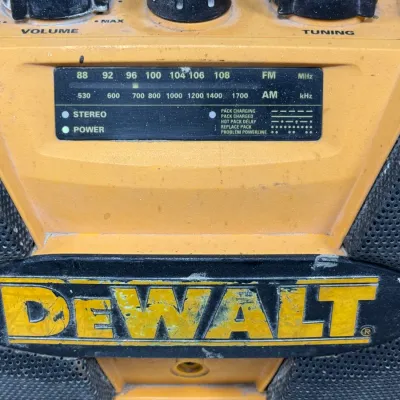 Sale Photo Thumbnail #908: Vintage DeWalt heavy-duty jobsite AM/FM radio and battery charger with a rugged yellow casing and dual side speakers, showing visible wear from use.