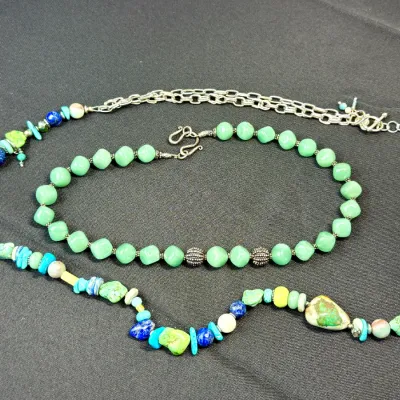 Sale Photo Thumbnail #22: Two beaded necklaces, including a light green gemstone strand with s-hook clasp and a longer multi-stone necklace featuring turquoise, lapis lazuli, and silver-tone chain accents.