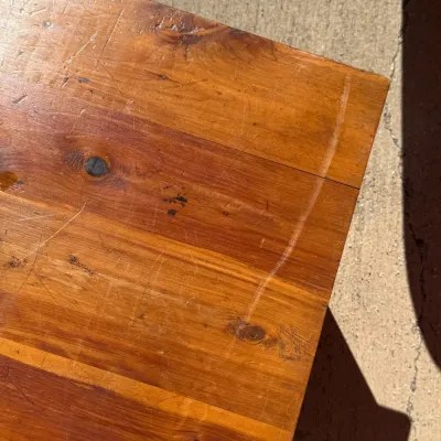 Sale Photo Thumbnail #323: Close-up of a wooden tabletop showing natural grain, knots, and surface scuffs.