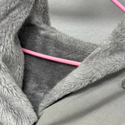 Sale Photo Thumbnail #868: Gray canvas jacket featuring a plush faux fur lining and wide collar, displayed on a pink plastic hanger.