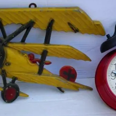 Vintage yellow cast iron biplane wall decor alongside a Bradley Mickey Mouse twin-bell alarm clock.