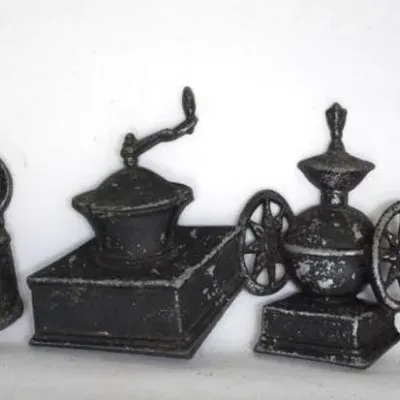 Collection of vintage cast iron miniatures, including a tea kettle, two coffee grinders, and a butter churn.