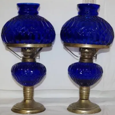 Pair of vintage cobalt blue pressed glass oil lamps with brass-toned bases and matching quilted glass shades.