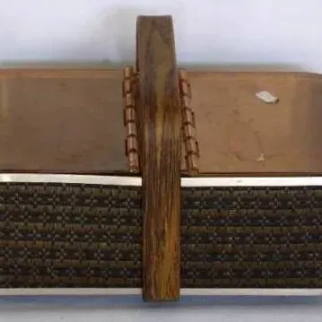 Vintage mid-century woven sewing basket with a faux wood grain handle and translucent amber plastic double-hinged lid.