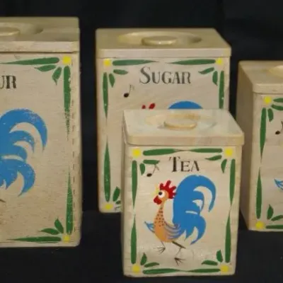 Vintage four-piece wooden kitchen canister set featuring hand-painted colorful rooster motifs and labeled for flour, sugar, coffee, and tea.