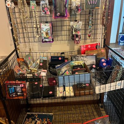 Black wire rolling display cart filled with costume jewelry, packaged accessories, games, and vinyl records, each individually priced.