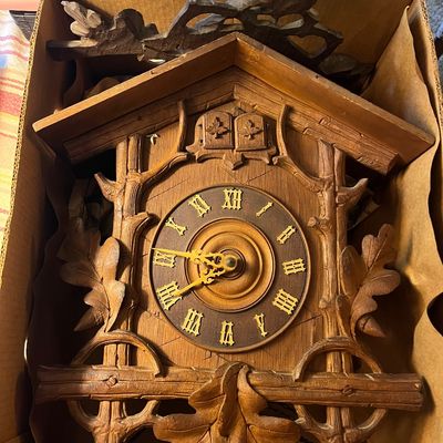 Vintage carved wood cuckoo clock featuring oak leaf and acorn motifs, complete with a top crown piece depicting a bird.