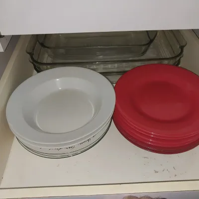 Sale Photo Thumbnail #18: Drawer containing stacks of white rimmed soup bowls, red plastic plates, and clear glass baking dishes.