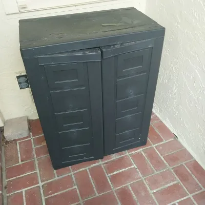 Sale Photo Thumbnail #27: Black resin two-door outdoor storage cabinet with panel details, showing light wear.