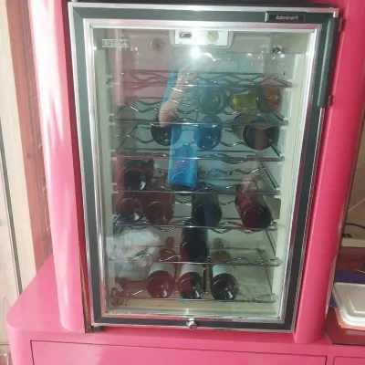 Sale Photo Thumbnail #12: Admiral 'The Wine Cellar' freestanding wine cooler refrigerator with glass door and multi-tier wire racks, housed inside a pink cabinet.