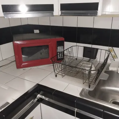 Sale Photo Thumbnail #14: Red Hamilton Beach countertop microwave sitting on a kitchen counter next to a metal wire dish drying rack.
