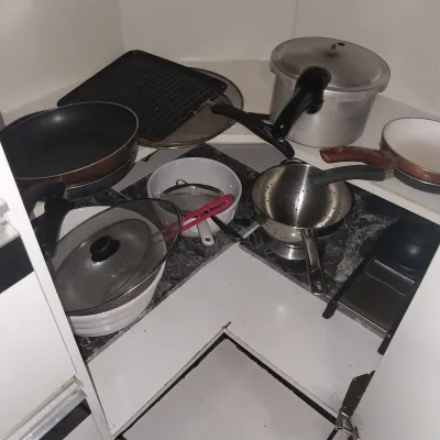 Sale Photo Thumbnail #30: Assorted cookware, including non-stick frying pans, a cast iron grill pan, an aluminum pressure cooker, stainless steel colanders, mesh strainers, and ceramic bowls.