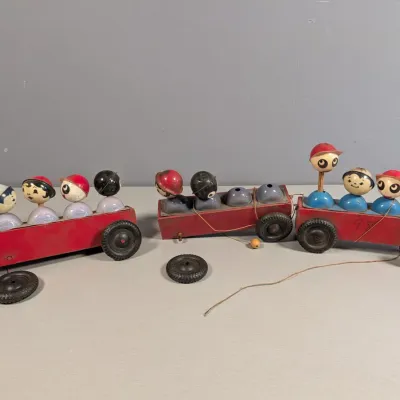Sale Photo Thumbnail #362: Vintage Fisher-Price wooden pull train with pop-up figure passengers, displaying wear and two loose wheels.