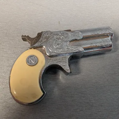 Sale Photo Thumbnail #311: Vintage Nichols 'Dynamite' derringer toy cap gun featuring an engraved-style chrome finish and faux-ivory grip with 'N' medallion.