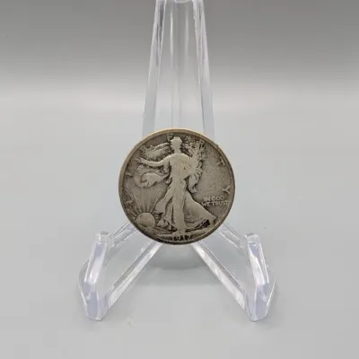 Sale Photo Thumbnail #17: 1917 Walking Liberty silver half dollar coin displayed on a clear plastic easel stand.