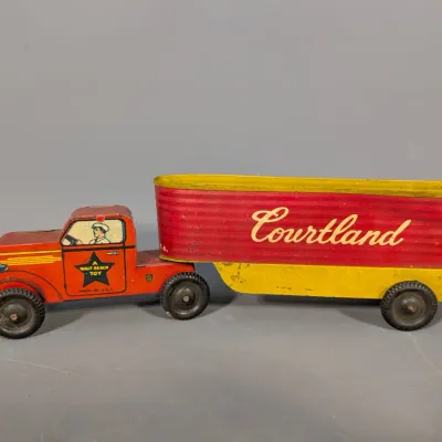 Sale Photo Thumbnail #414: Vintage Courtland lithographed tin friction semi-truck and trailer toy with red and yellow paint, featuring Walt Reach Toy branding and minor play wear.